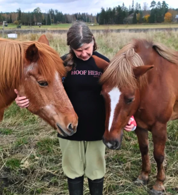 Pia standing between her two horses in Finland.